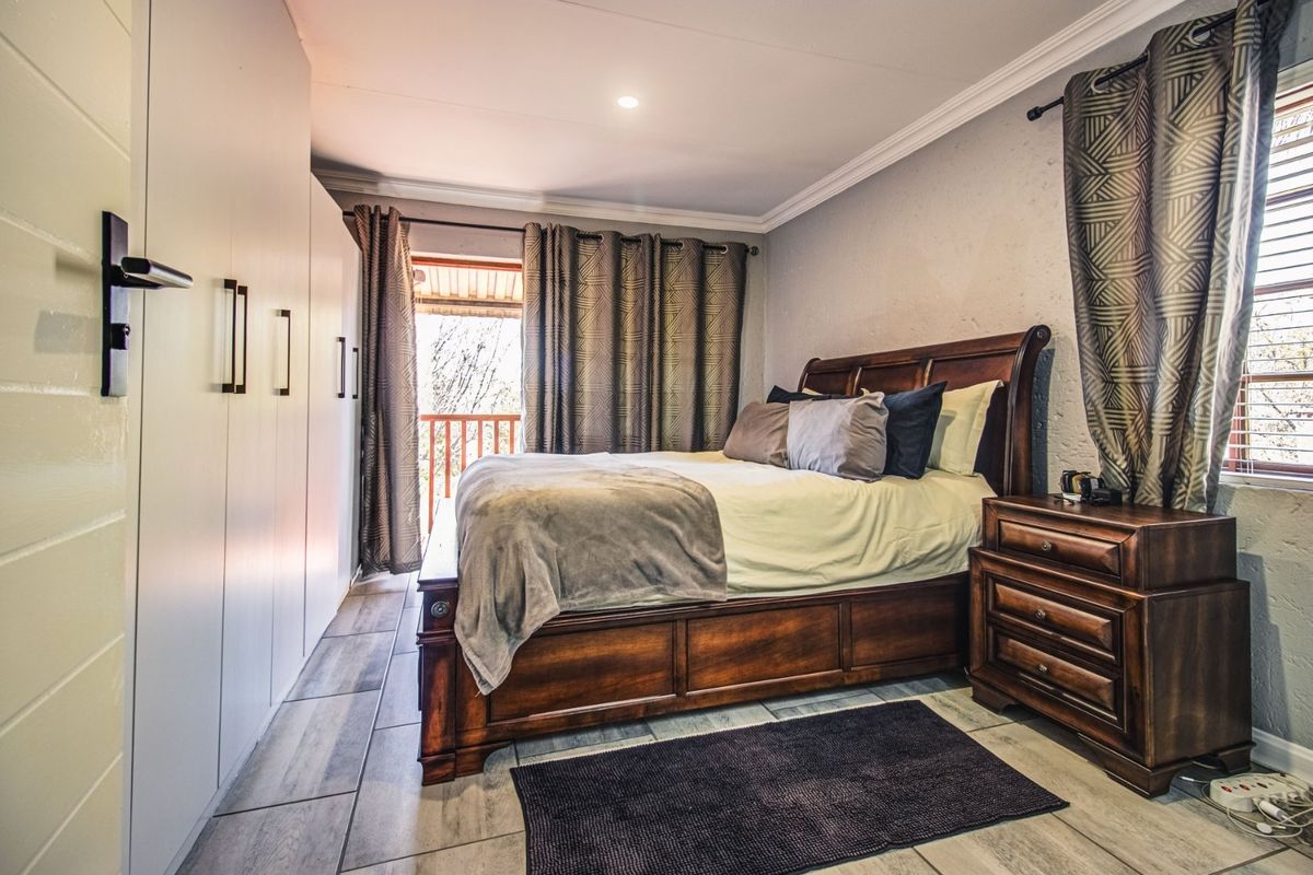 A well-maintained bedroom featuring built-in cupboards, tiled flooring, and direct access to a private balcony through a sliding door.