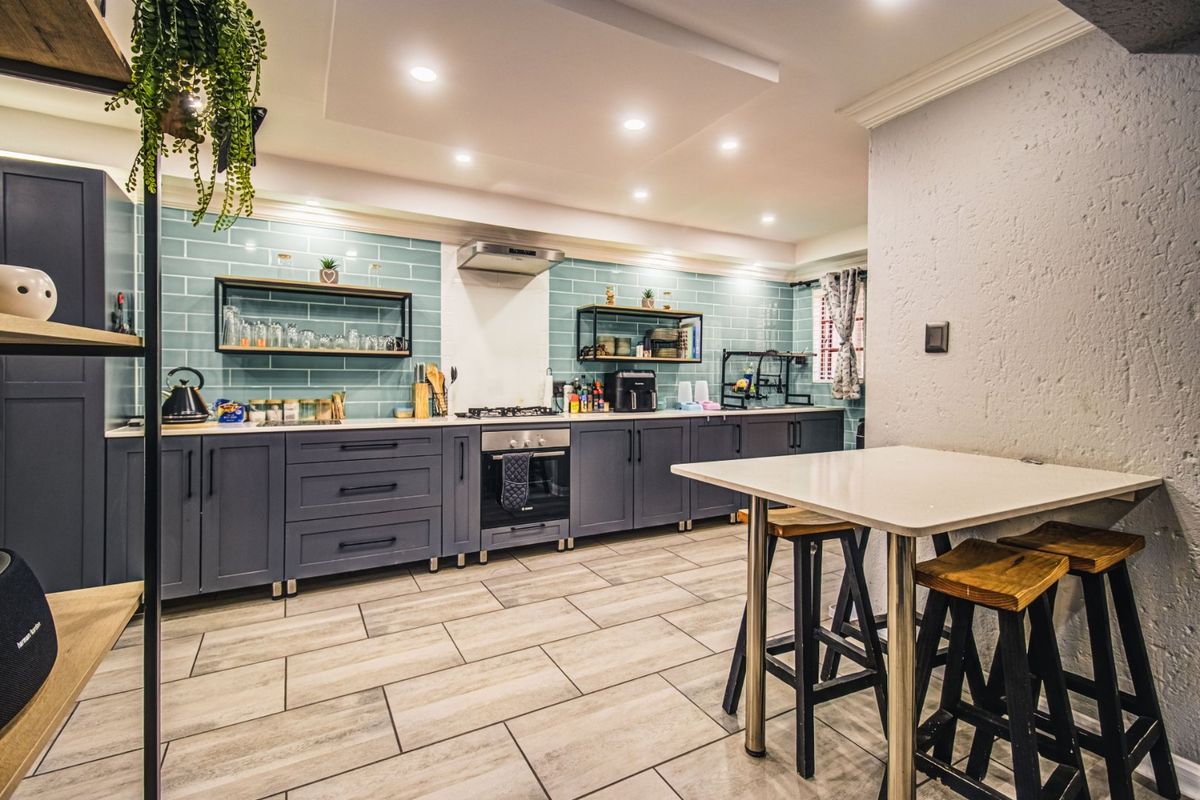 Modern kitchen featuring dark cabinetry, light stone countertops, a stylish subway tile backsplash, built-in oven, gas hob, and recessed lighting.