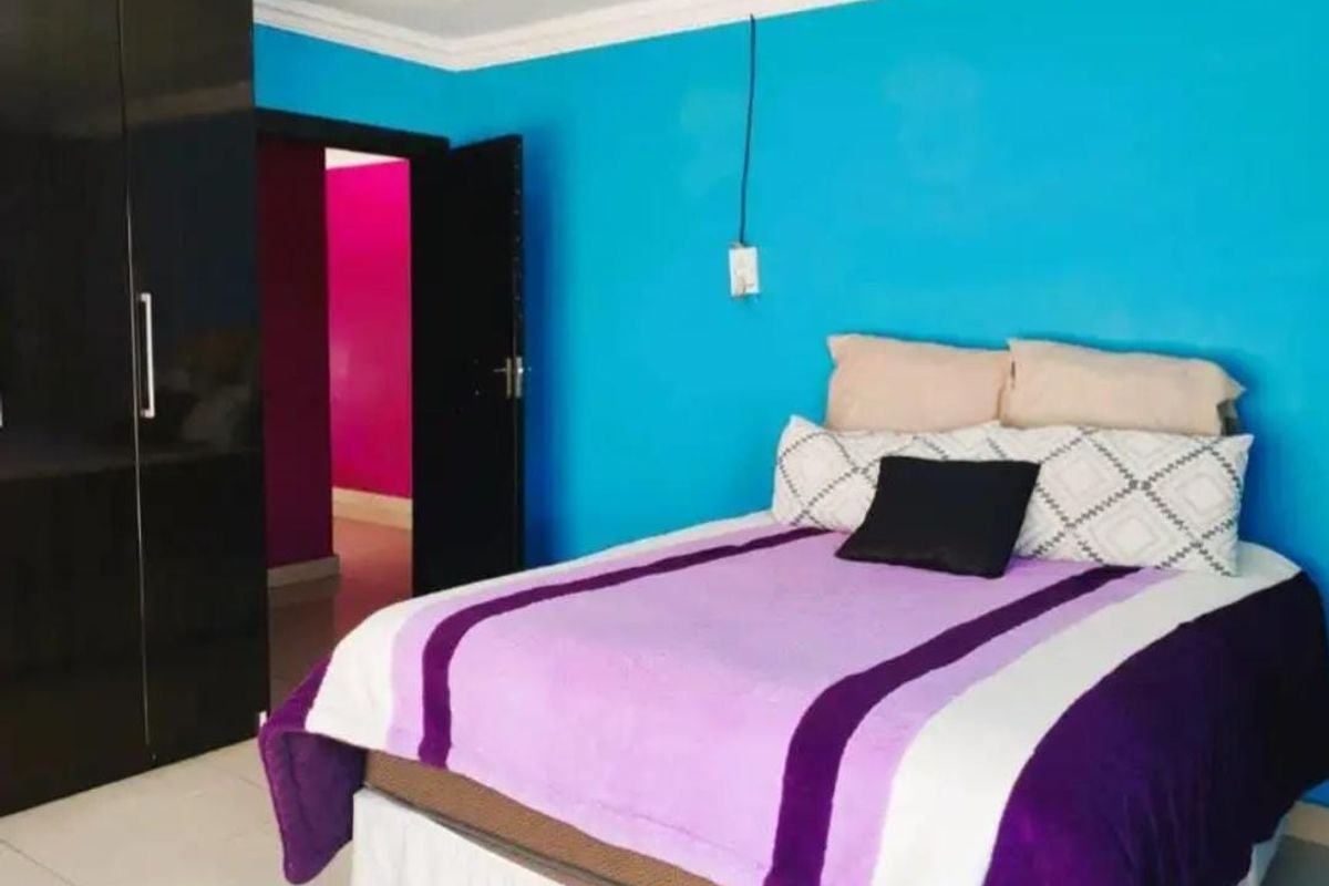 A bedroom featuring built-in cupboards and tiled flooring, with bright blue wall paint.