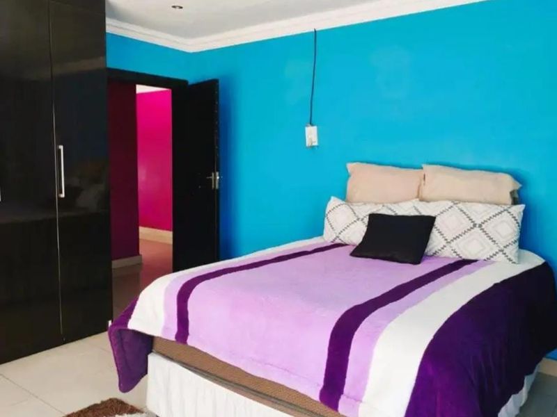 A bedroom featuring built-in cupboards and tiled flooring, with bright blue wall paint.
