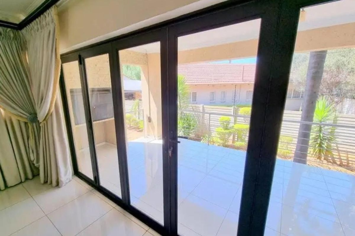 Bright living area featuring large black-framed sliding glass doors that open onto a covered patio with tiled flooring.