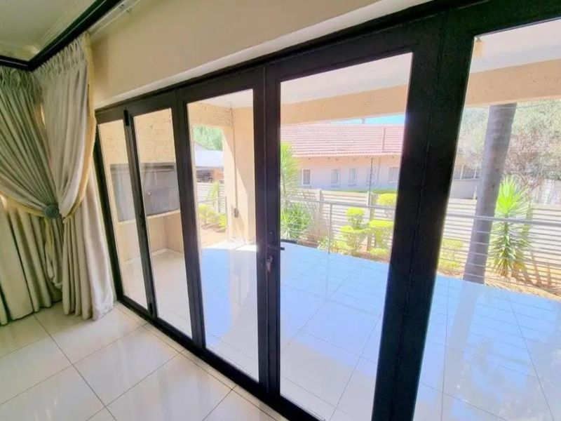 Bright living area featuring large black-framed sliding glass doors that open onto a covered patio with tiled flooring.
