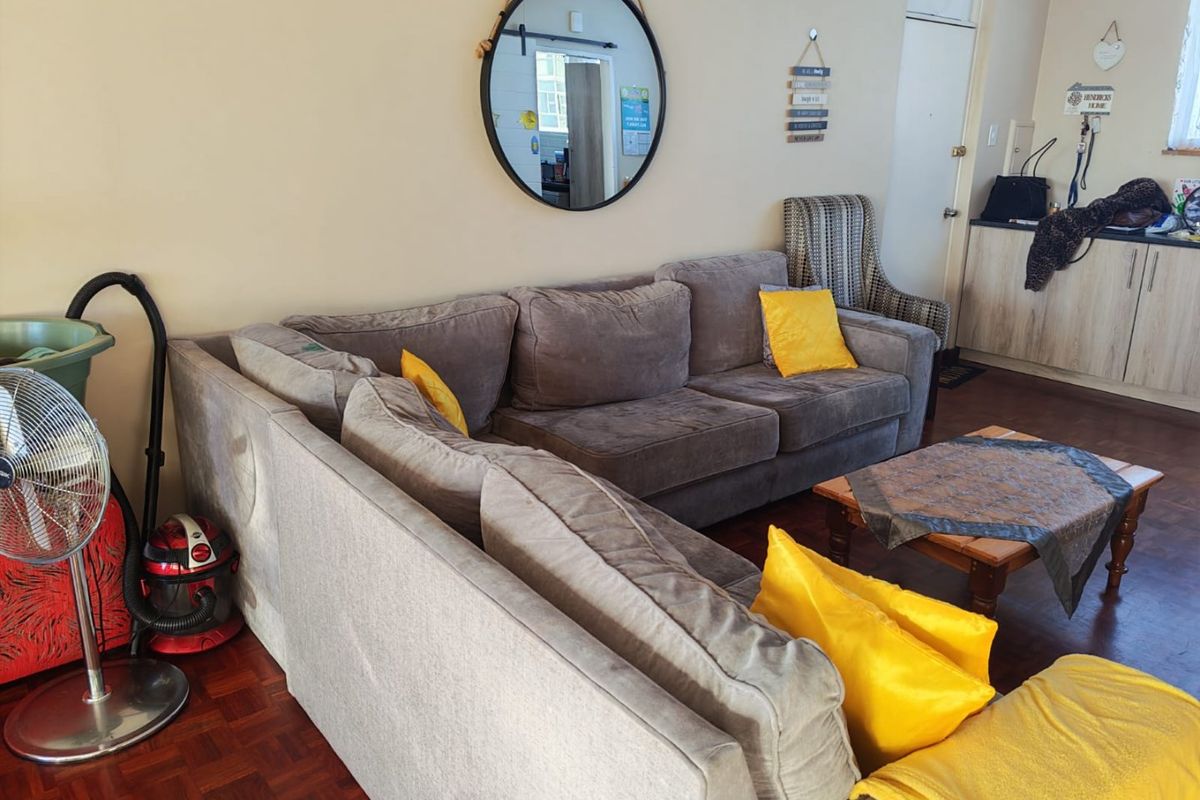 A living area featuring parquet flooring and a built-in kitchen cabinet unit in the background.
