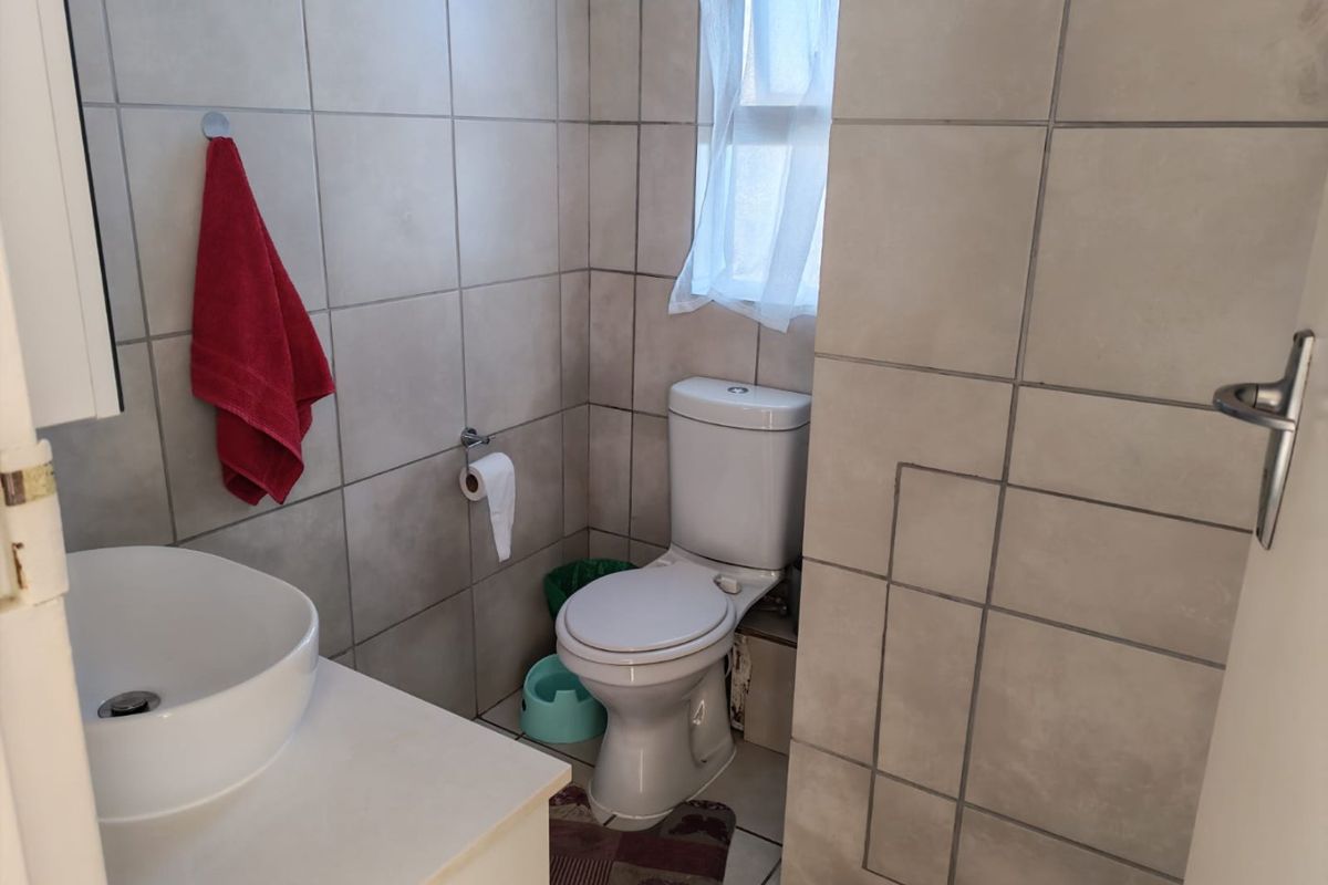 A compact bathroom featuring neutral wall tiles, a modern vessel sink vanity, and a standard toilet.