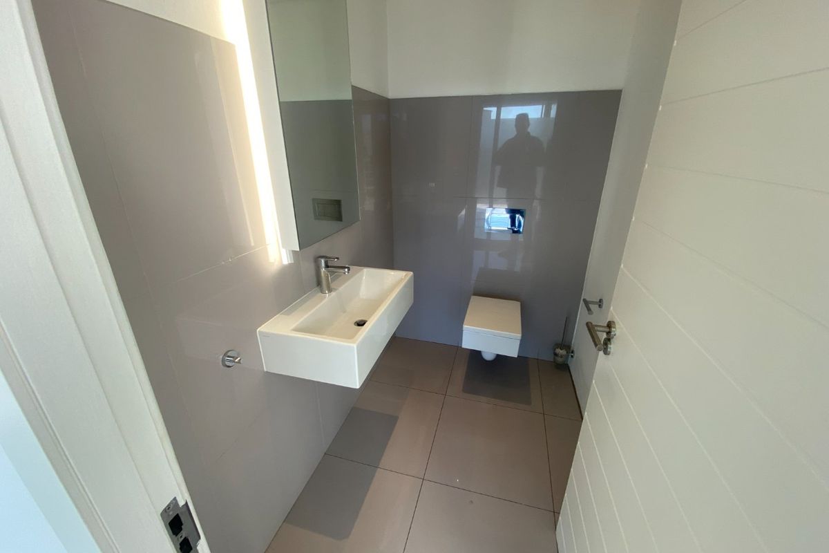 Modern guest bathroom featuring a wall-mounted vanity basin, sleek wall-hung toilet, and contemporary grey tiled finishes.
