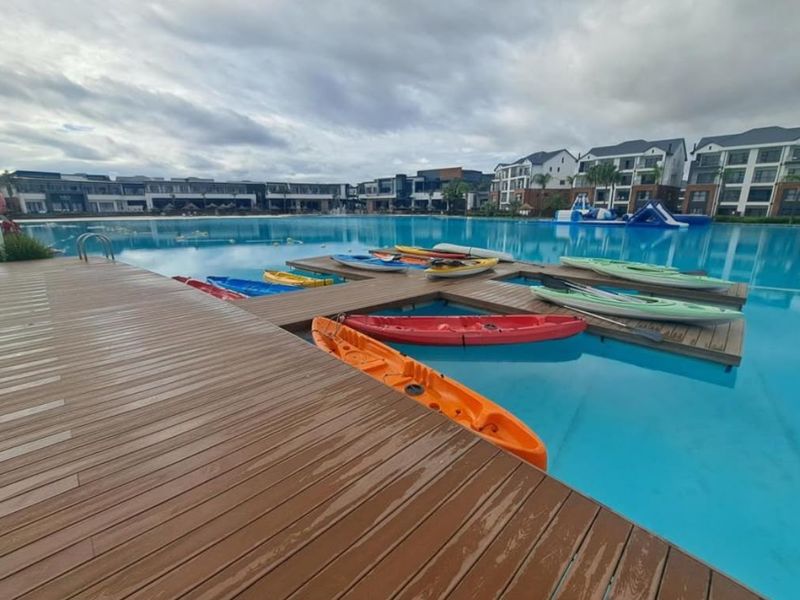 A large communal swimming pool area featuring a wooden jetty and surrounding apartment complex buildings.
