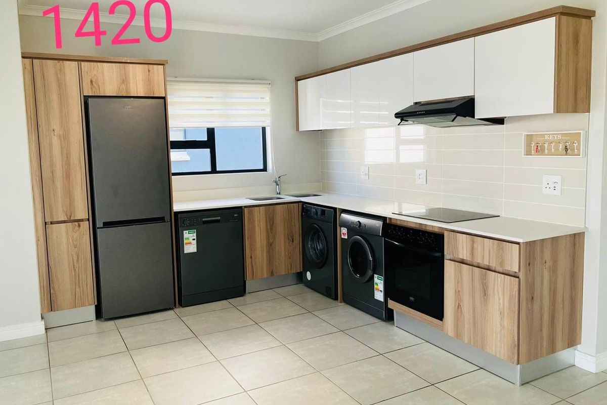 Modern kitchen featuring wood-grain cabinetry, white countertops, tiled flooring, and integrated appliances including an oven, hob, and extractor fan.