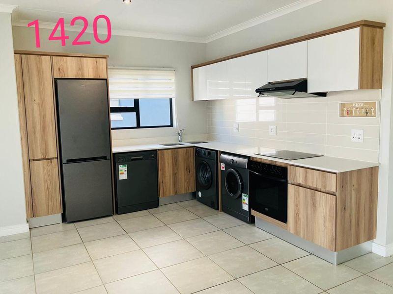 Modern kitchen featuring wood-grain cabinetry, white countertops, tiled flooring, and integrated appliances including an oven, hob, and extractor fan.