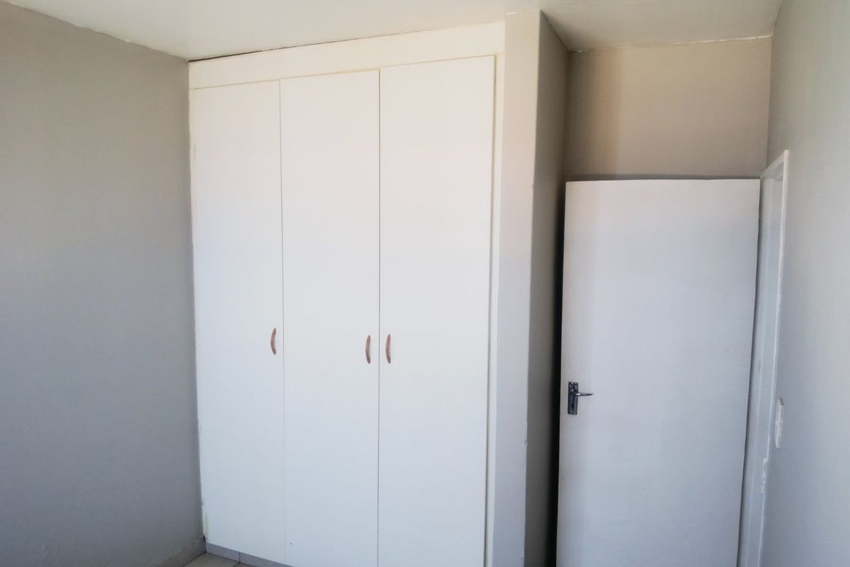 A bedroom interior featuring built-in white cabinetry and a standard door, providing functional storage space.