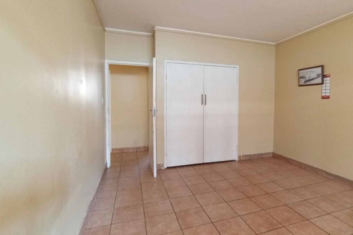 A simple bedroom featuring tiled flooring and a built-in wardrobe with double doors.