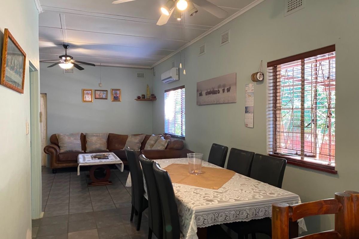 Open plan living and dining area featuring tiled flooring, ceiling fans, and a wall-mounted air conditioning unit.