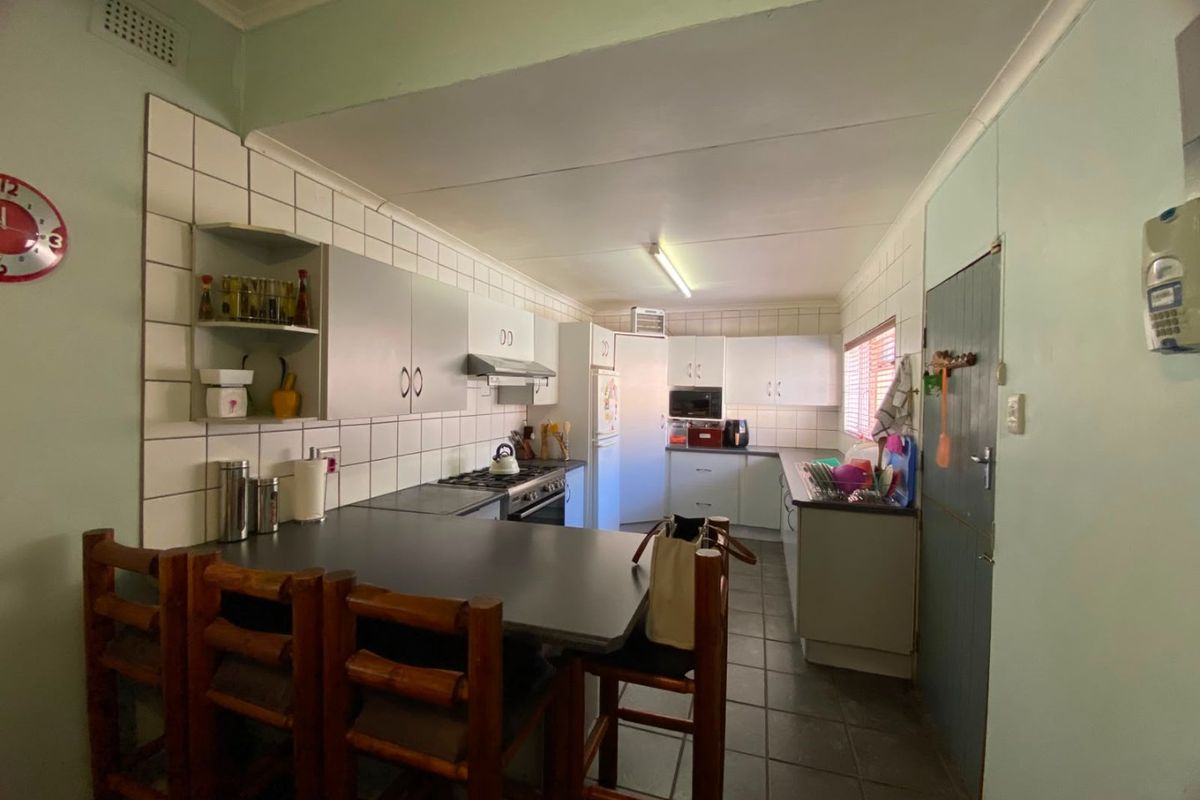 A functional kitchen featuring built-in cabinetry, a breakfast bar, tiled splashbacks, and integrated cooking appliances.