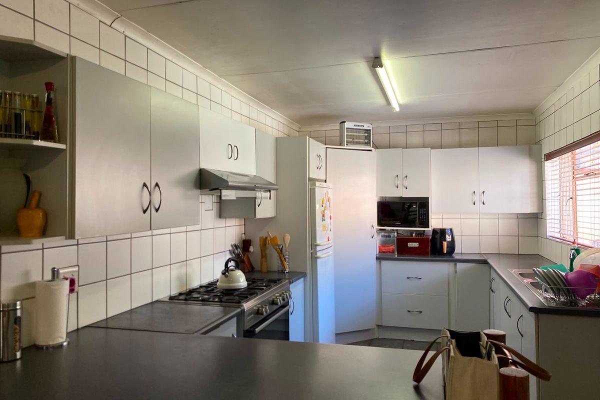 Functional kitchen featuring white cabinetry, dark countertops, built-in gas hob, extractor fan, and tiled splashbacks.