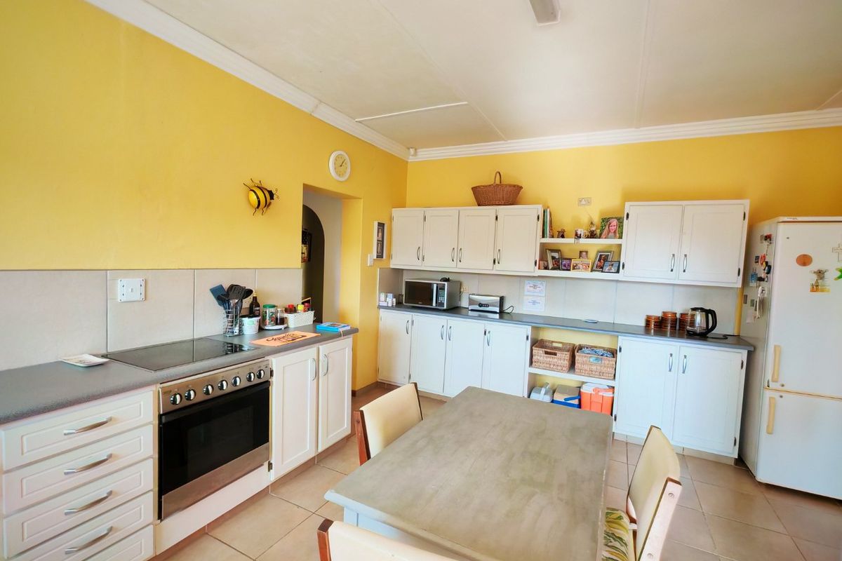 A functional kitchen featuring white cabinetry, tiled flooring, and a built-in electric oven and hob, providing a practical workspace for daily meal preparation.