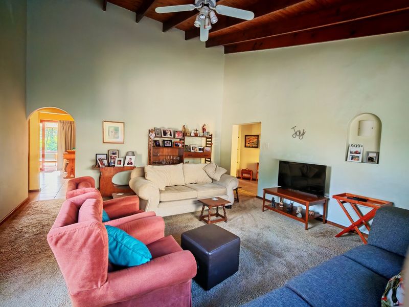 Spacious living room featuring high vaulted ceilings with exposed timber beams and a classic arched doorway leading to an adjacent area.
