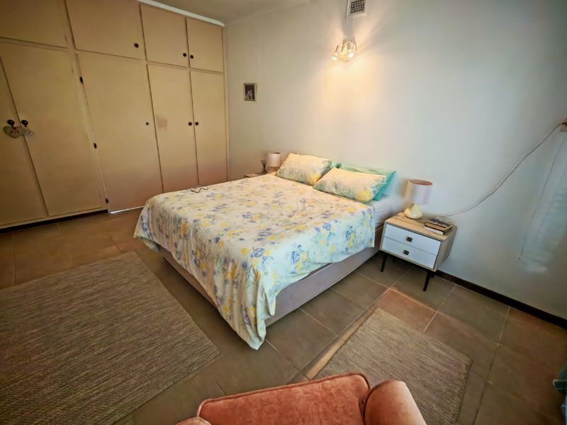 A bedroom featuring built-in floor-to-ceiling cabinetry and tiled flooring, providing functional storage space.