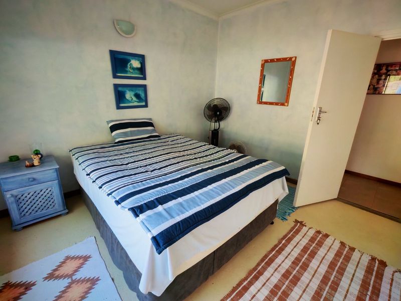 A functional bedroom featuring neutral wall finishes, tiled flooring, and a standard door leading to an adjacent space.