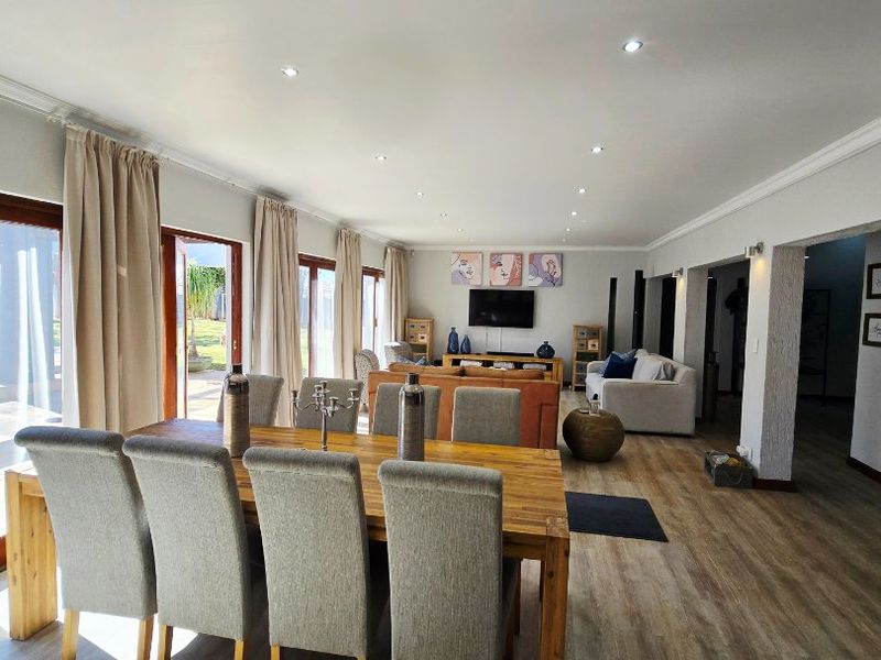 Spacious open-plan living and dining area featuring modern laminate flooring, recessed lighting, and large sliding glass doors providing ample natural light.