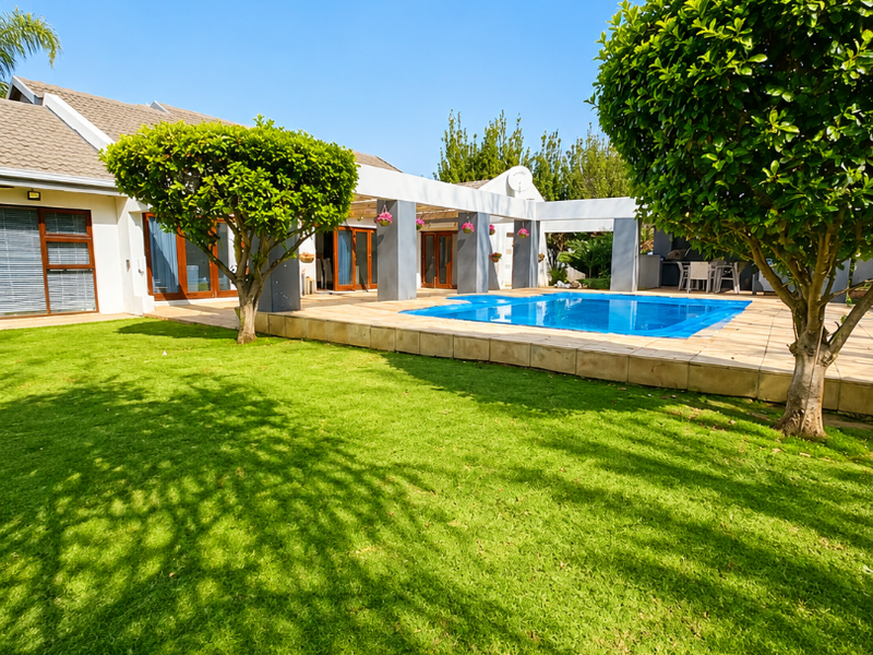 A well-maintained rear exterior featuring a swimming pool, tiled patio area with a pergola, and a spacious manicured lawn.