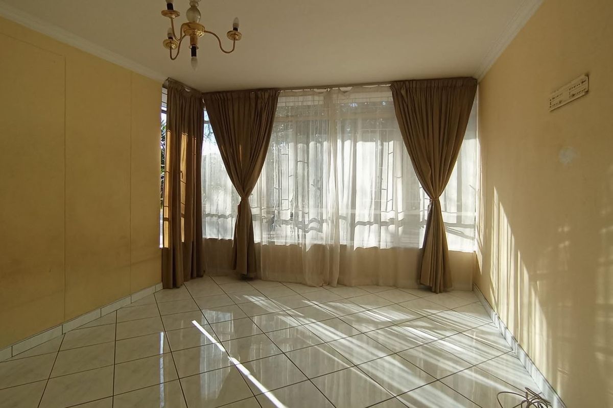 A bright, empty living room featuring large windows with curtains and tiled flooring, offering a clean and versatile space for personalization.