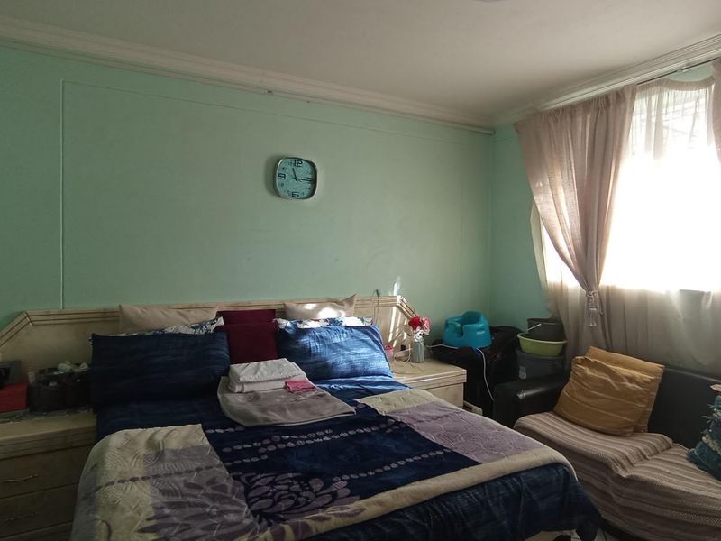 A bedroom featuring a built-in headboard with integrated bedside tables and a window with curtains.