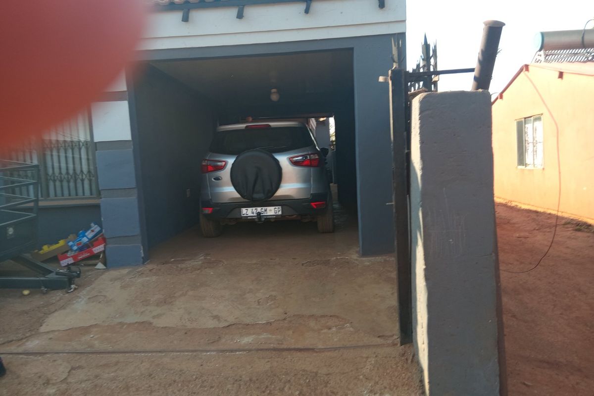 A covered garage area with a concrete driveway and perimeter walling, providing secure off-street parking.