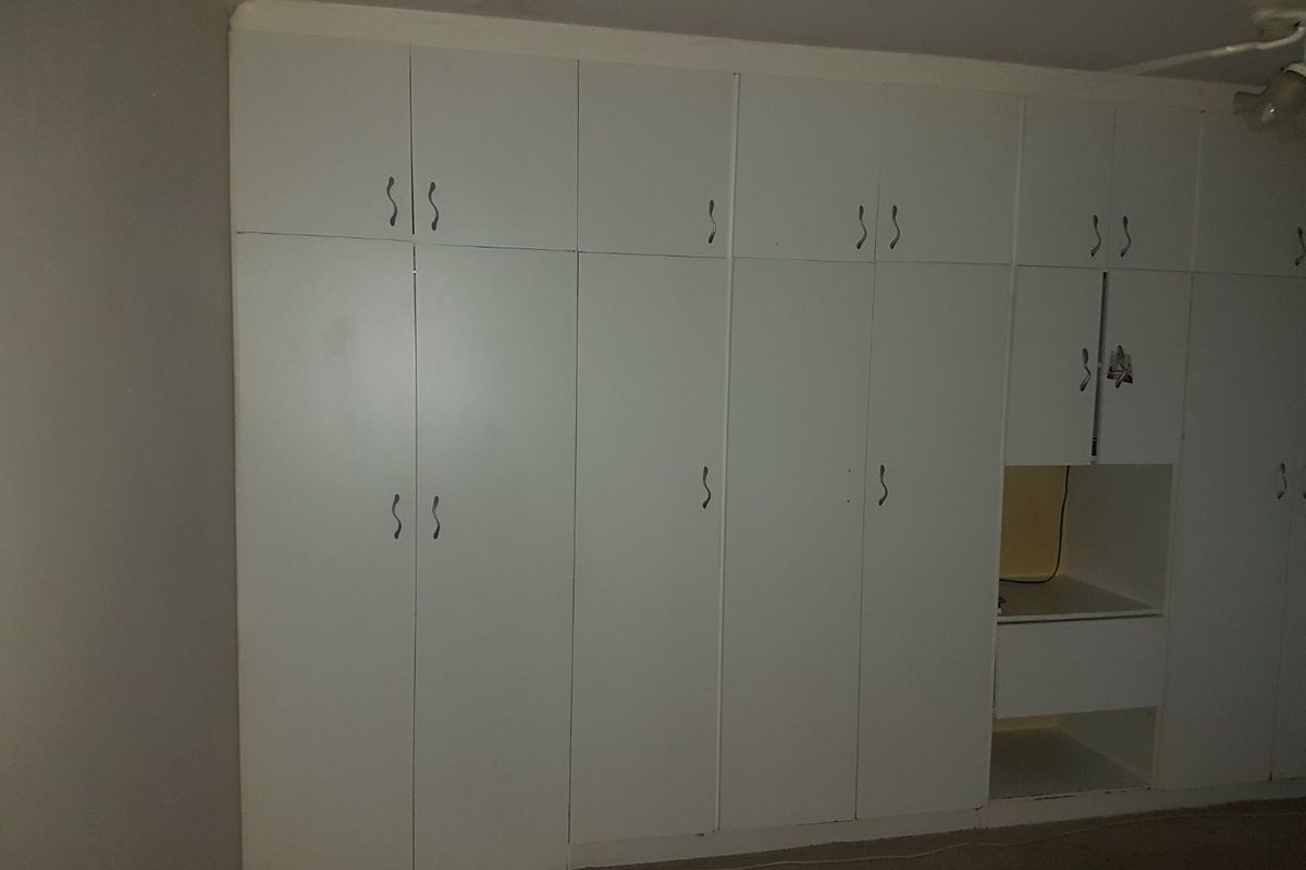 A bedroom featuring extensive floor-to-ceiling built-in white cabinetry with integrated shelving and storage compartments.