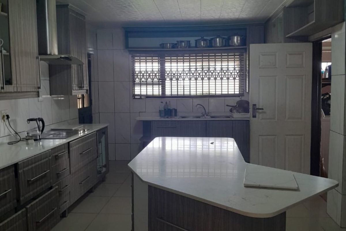 A functional kitchen featuring a central island, built-in cabinetry, tiled flooring, and a stainless steel extractor fan.