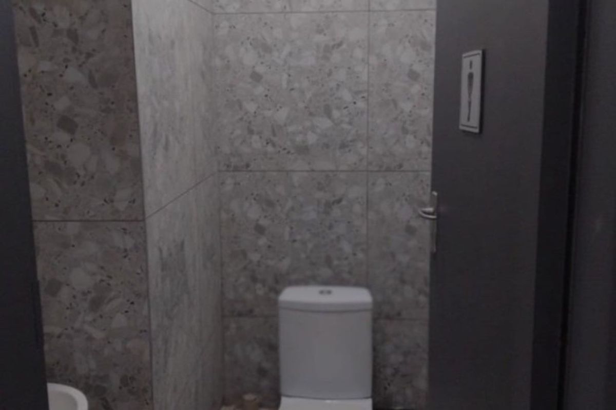 A compact guest bathroom featuring modern terrazzo-style wall tiling, a standard toilet, and a small wall-mounted basin.