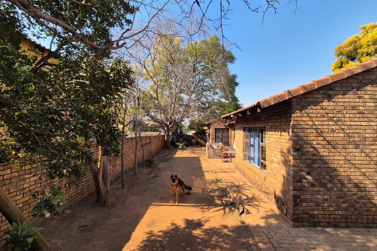A view of the rear exterior of the house featuring face-brick walls, a paved walkway, and a garden area.