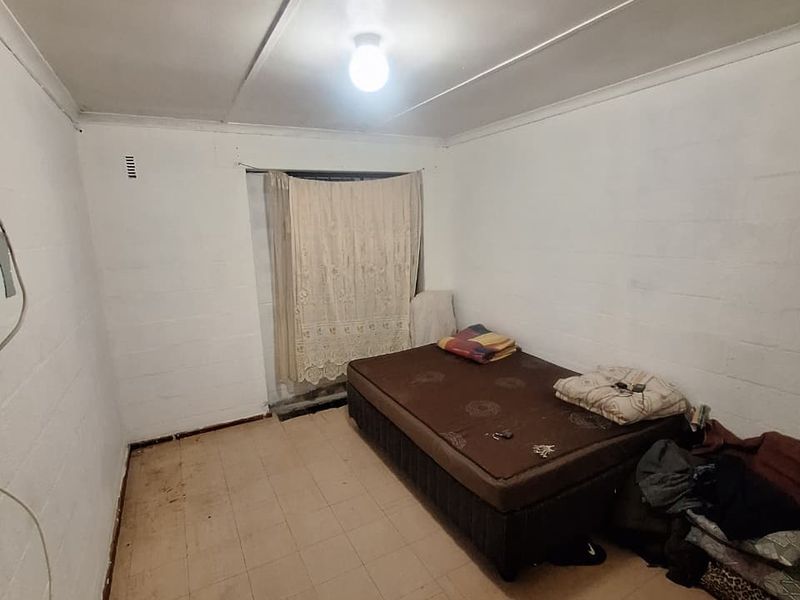 A basic bedroom featuring painted block walls, tiled flooring, and a simple ceiling light fixture.