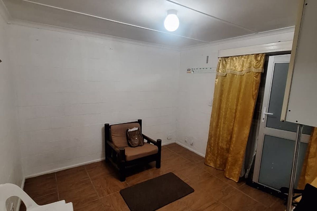 A simple, functional room featuring tiled flooring, a glass-panelled exterior door, and basic lighting fixtures, suitable for a bedroom or home office space.