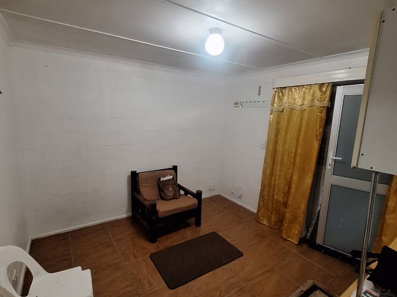 A simple, functional room featuring tiled flooring, a glass-panelled exterior door, and basic lighting fixtures, suitable for a bedroom or home office space.