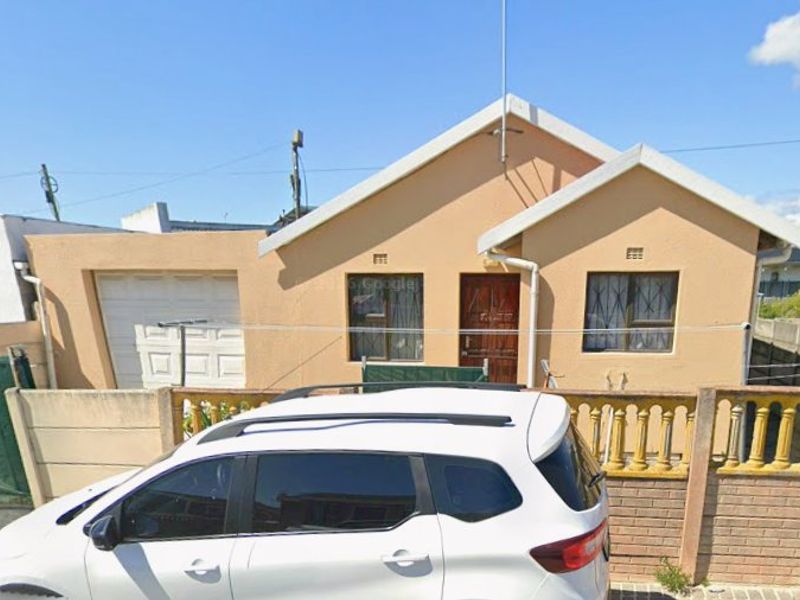 Front elevation of a single-story residential house featuring a tiled roof, attached garage, and perimeter boundary wall with gated access.