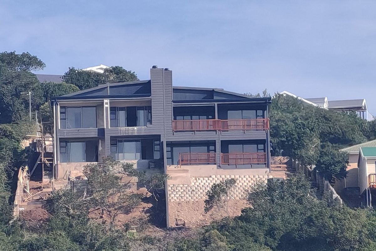 Elevated view of a multi-story residential property featuring large glass sliding doors, timber balconies, and a prominent central chimney stack.