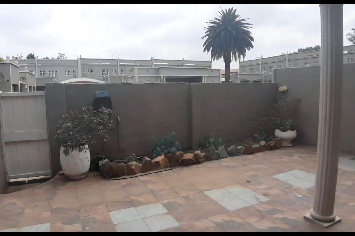 A private rear patio area featuring paved flooring, a perimeter boundary wall, and a structural support column, offering a low-maintenance outdoor space.