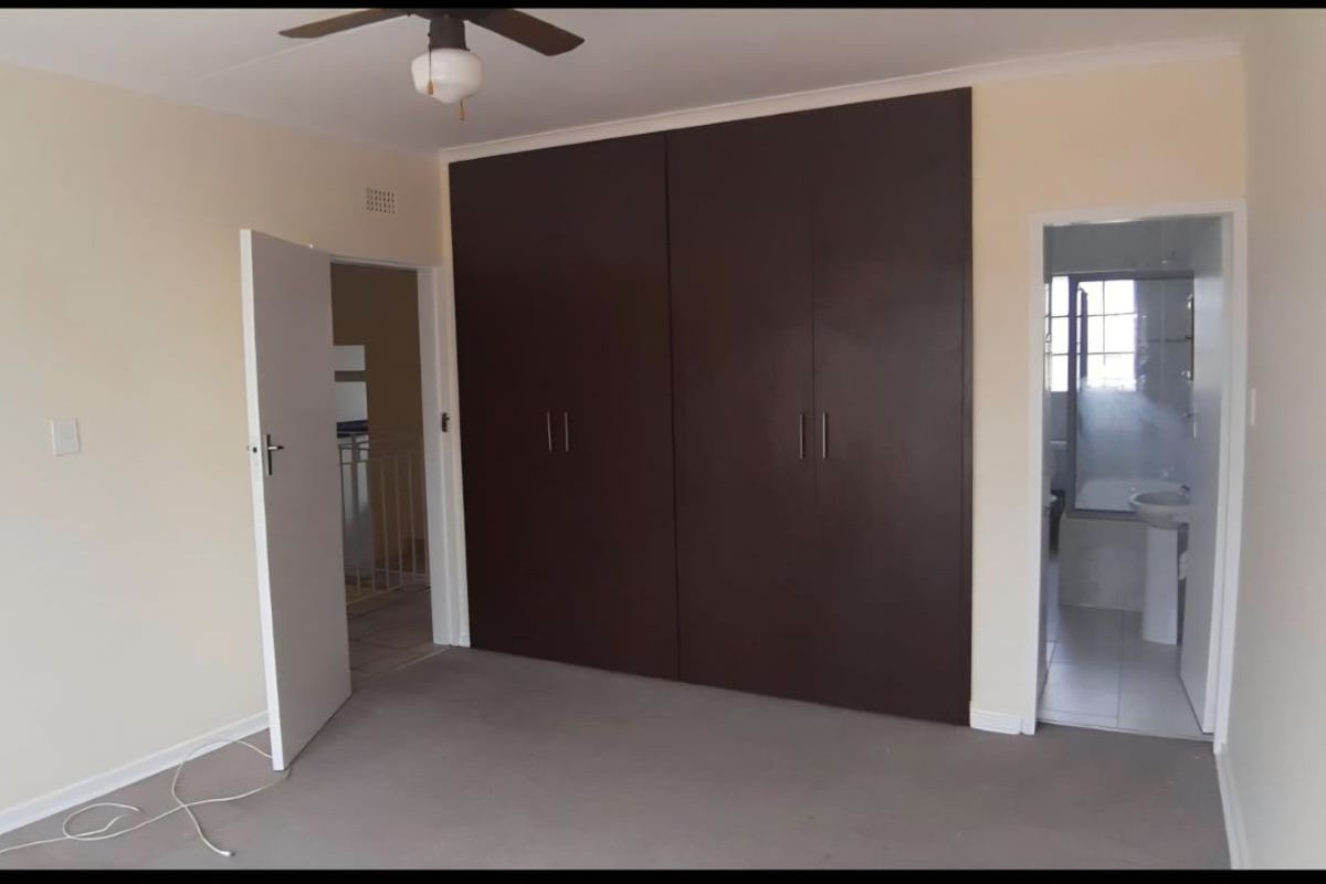 A bedroom featuring built-in dark wood cabinetry, neutral wall finishes, and direct access to an en-suite bathroom.