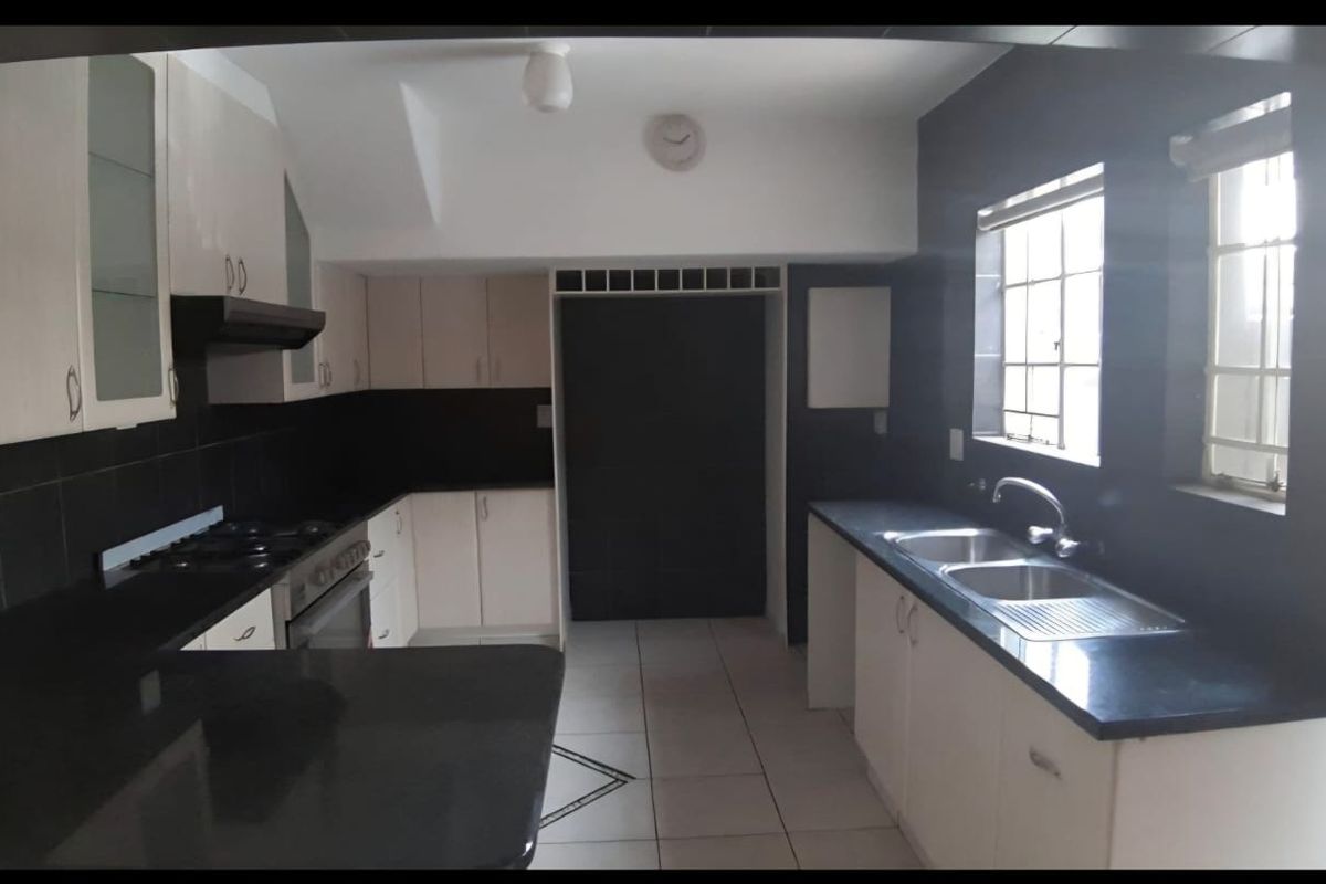 A functional kitchen featuring dark granite countertops, white cabinetry, a built-in stove with extractor fan, and a double stainless steel sink.