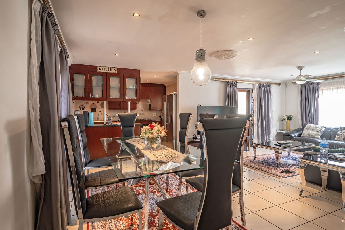 Open-plan living and dining area featuring tiled flooring, recessed lighting, and a functional kitchen with built-in cabinetry.