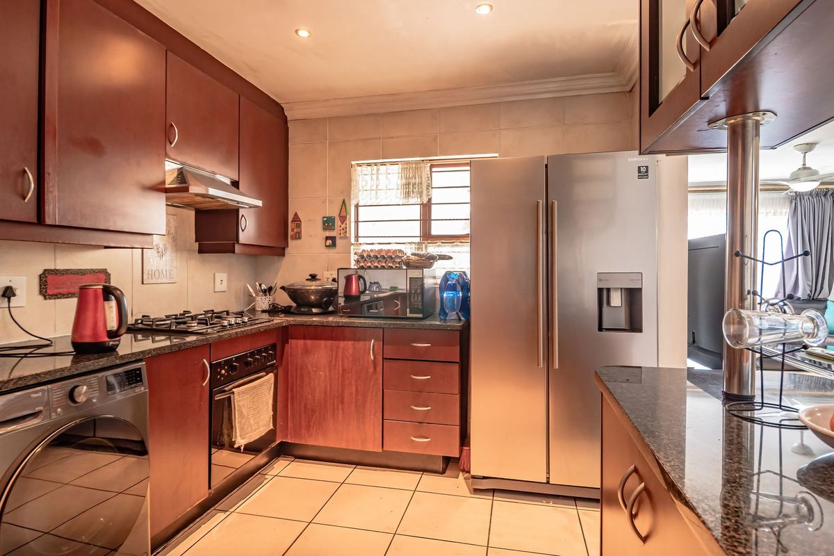 A functional kitchen featuring dark wood cabinetry, granite countertops, a built-in gas hob, oven, and integrated space for a large refrigerator.