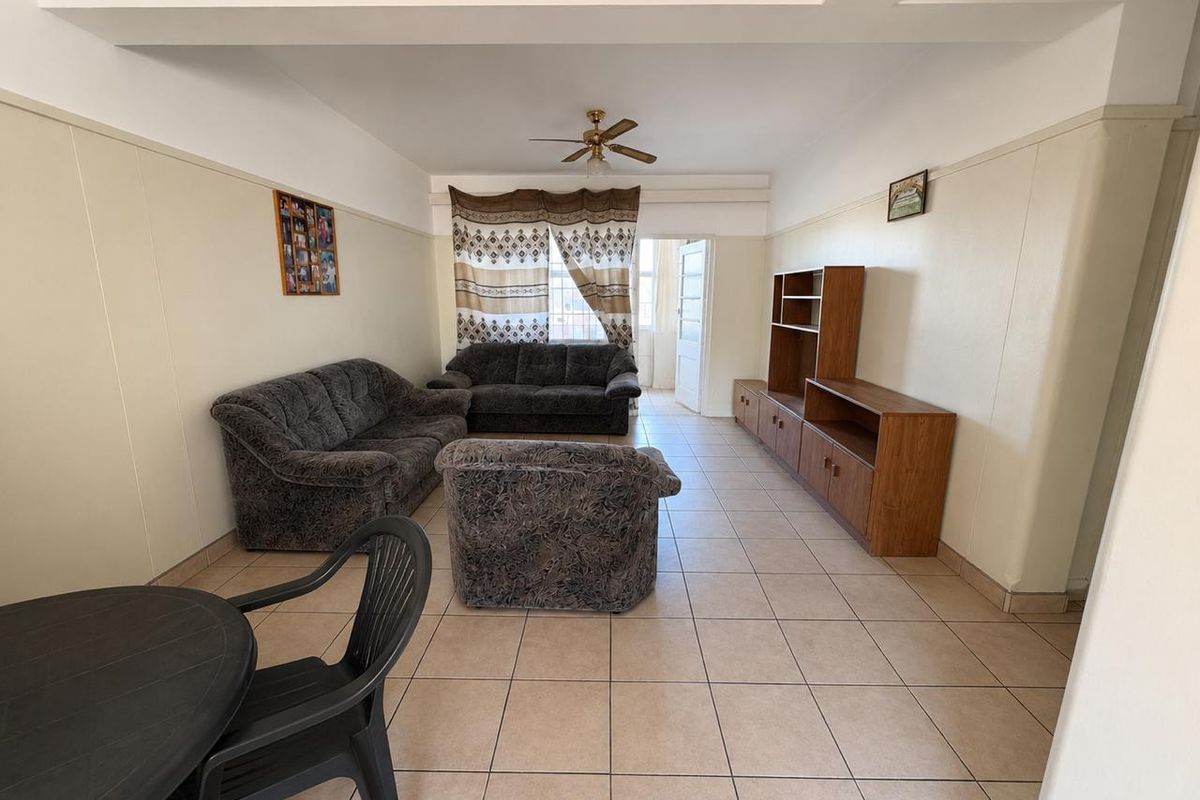 Spacious living area featuring neutral tiled flooring, a ceiling fan, and direct access to an outdoor balcony space.