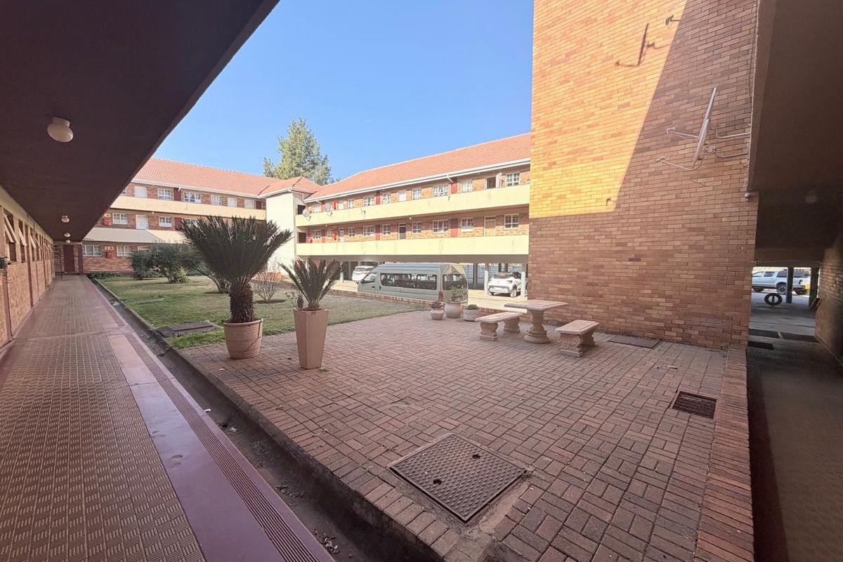 A communal courtyard area featuring brick paving and landscaped garden space within an apartment complex.