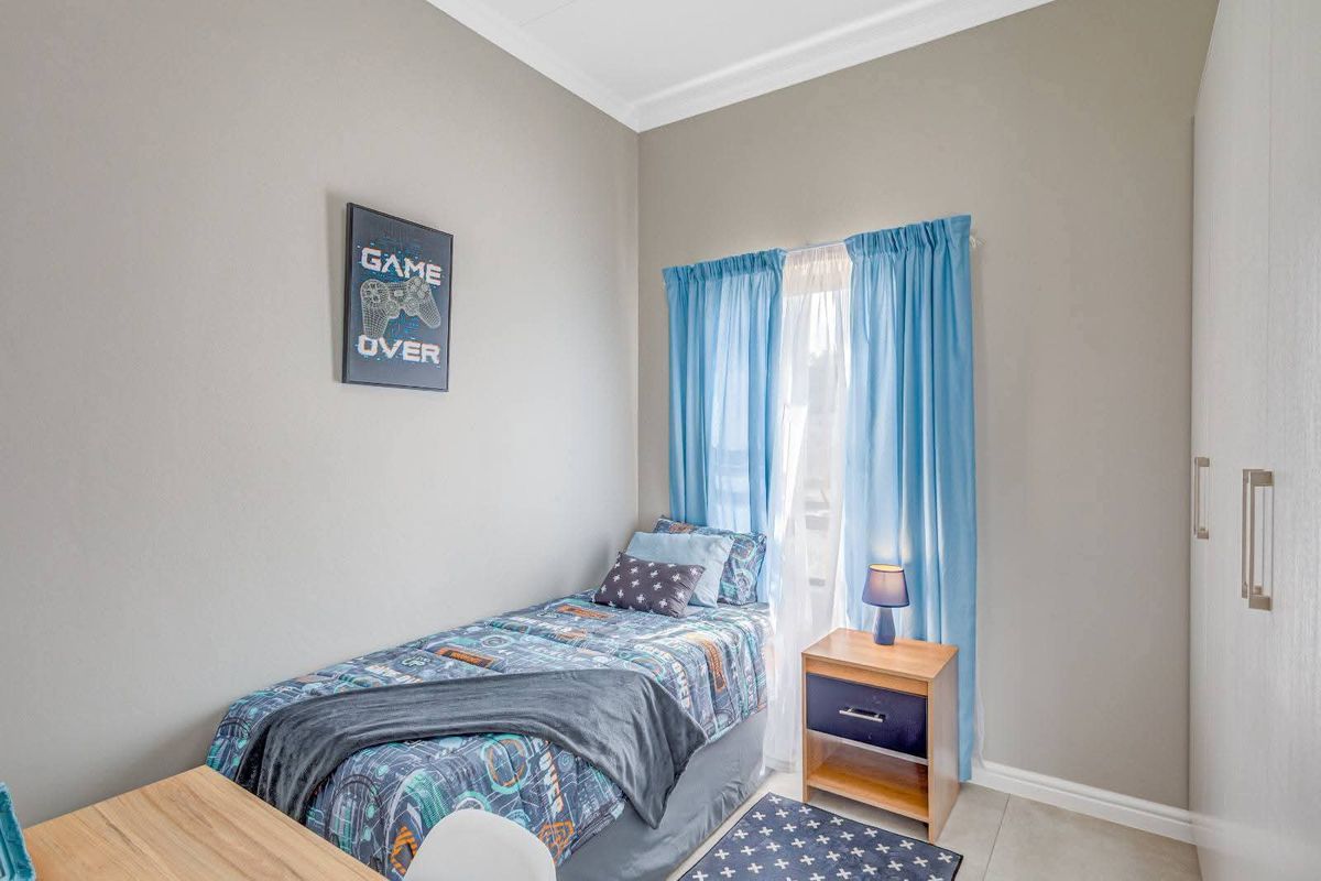A well-maintained bedroom featuring neutral wall tones, tiled flooring, and built-in wardrobe storage.