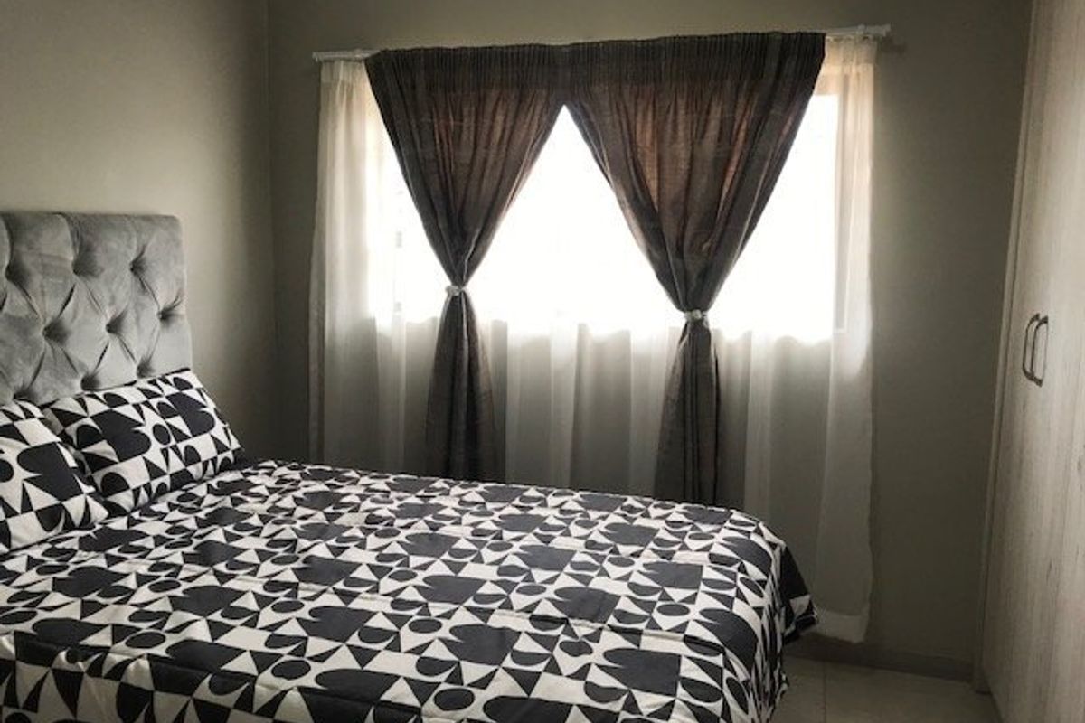 A bedroom featuring built-in cupboards and tiled flooring, providing a functional and neutral living space.