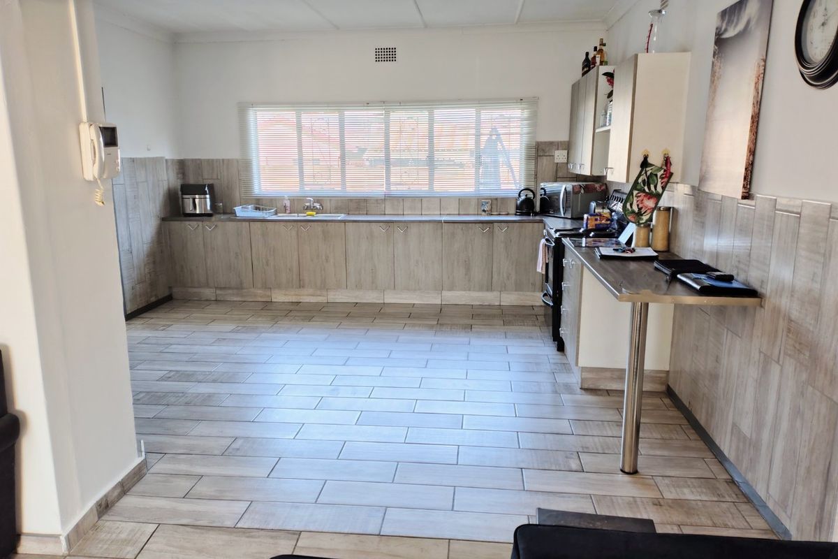 A functional kitchen featuring wood-look cabinetry, tiled splashbacks, tiled flooring, and a breakfast bar counter.