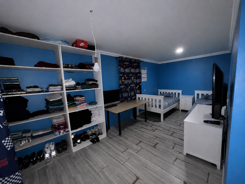 A bedroom featuring blue painted walls, tiled flooring, and built-in open shelving units.