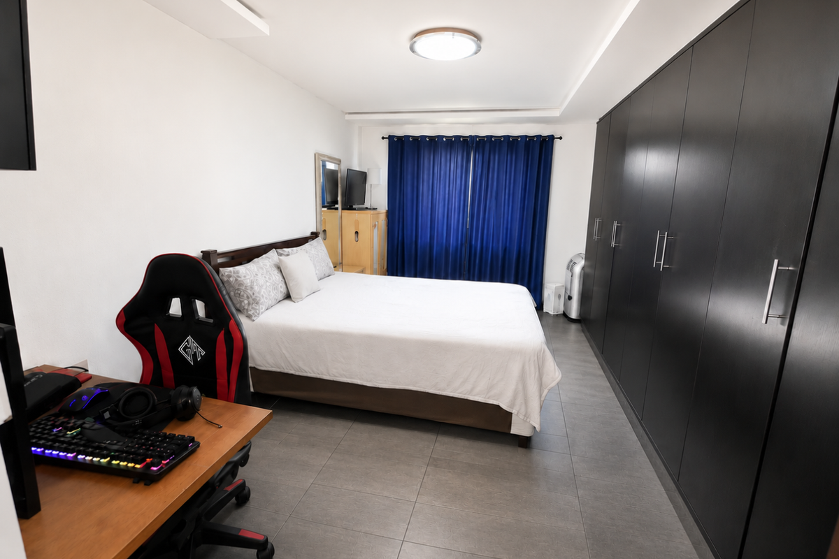 A well-maintained bedroom featuring large built-in floor-to-ceiling wardrobes, tiled flooring, and recessed ceiling lighting.