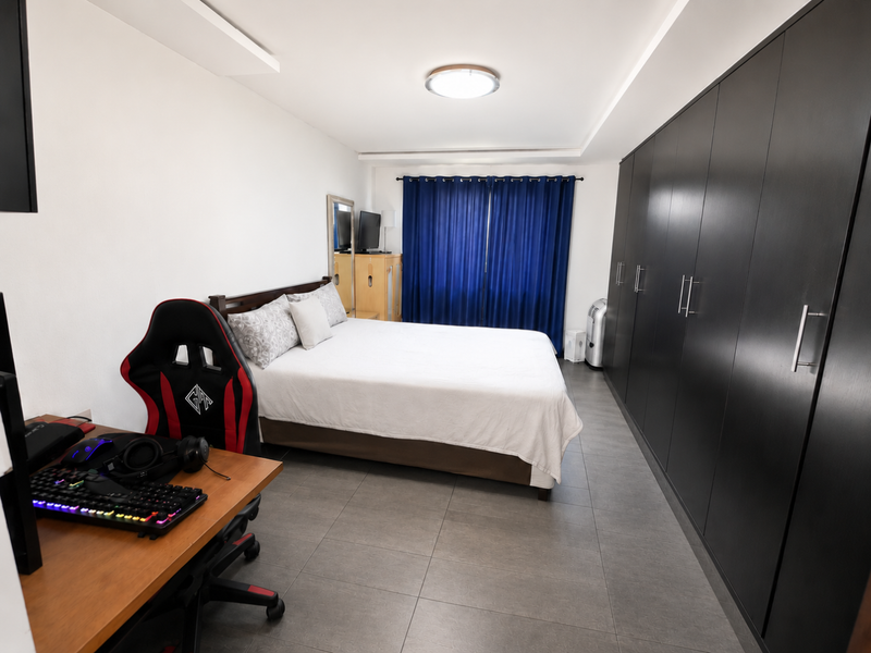 A well-maintained bedroom featuring large built-in floor-to-ceiling wardrobes, tiled flooring, and recessed ceiling lighting.
