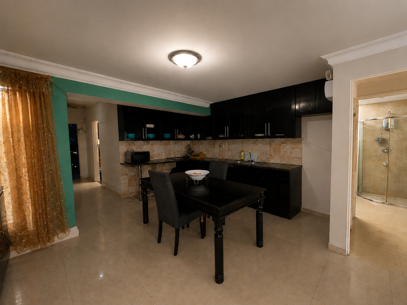 Open plan kitchen featuring dark cabinetry, tiled backsplash, and tiled flooring, with an adjacent bathroom visible through the doorway.