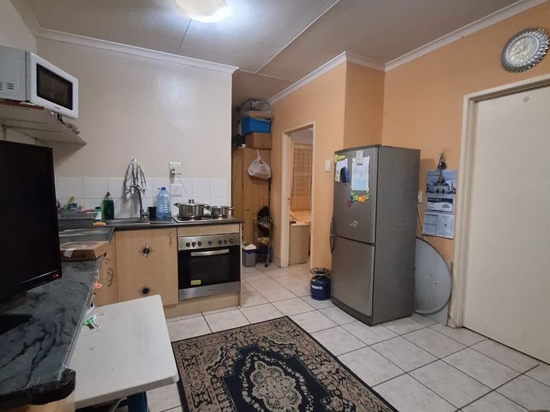 A functional kitchen featuring built-in cabinetry, an integrated oven and hob, tiled flooring, and direct access to adjacent rooms.